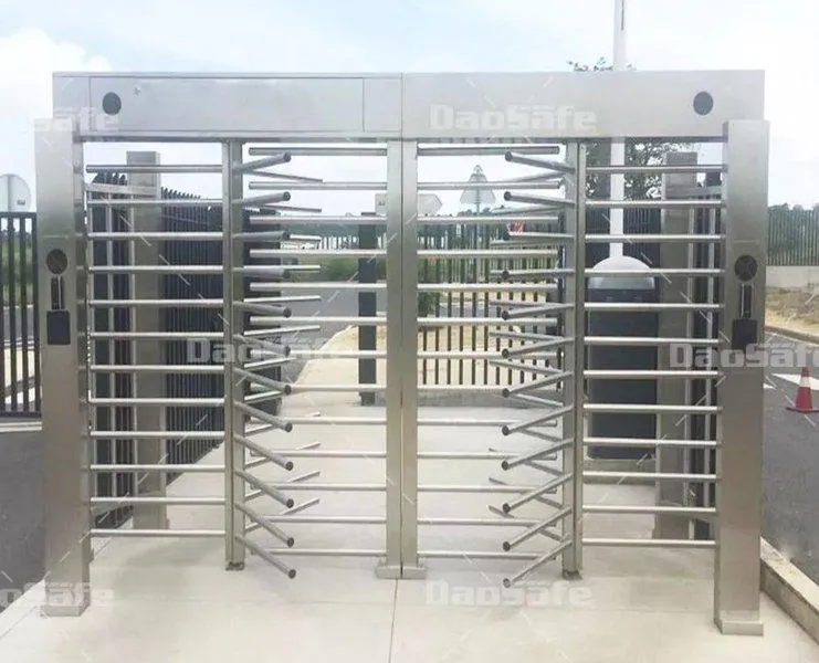 Dvojitý celotelový prístupový turniket DS411 z brúsenej nehrdzavejúcej ocele, s vertikálnymi barmi a horizontálnymi rotačnými ramenami, nainštalovaný vo vonkajšom prostredí pre kontrolu vstupu do zabezpečeného areálu, s čítačkami kariet na oboch stranách.